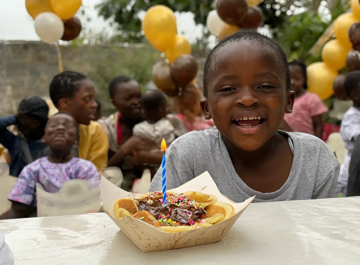 Un enfant devant sa barquette de mini pancakes avec une bougie d’anniversaire